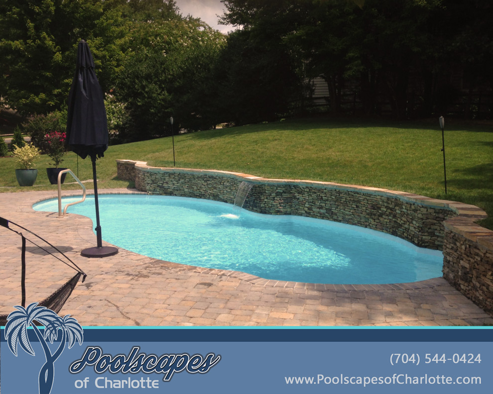 На фото: бассейн среднего размера, произвольной формы на заднем дворе в классическом стиле с покрытием из каменной брусчатки