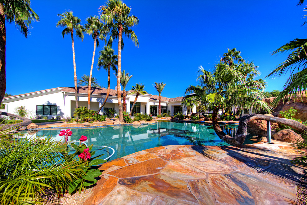 На фото: огромный бассейн произвольной формы на заднем дворе в современном стиле с фонтаном и покрытием из каменной брусчатки