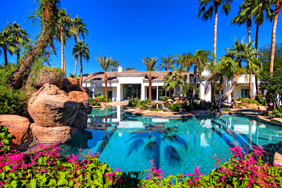 Pool fountain - huge tropical backyard stone and custom-shaped pool fountain idea in Phoenix