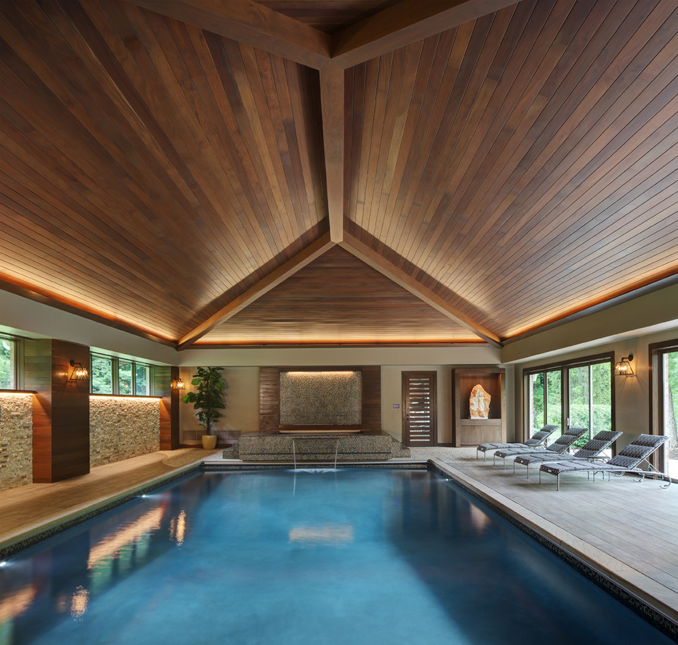 Cette photo montre une piscine intérieure tendance rectangle avec un point d'eau et une terrasse en bois.