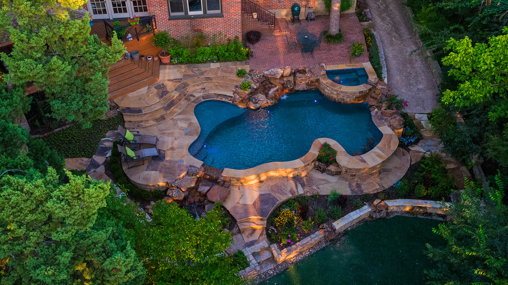 Ejemplo de piscina natural rústica de tamaño medio a medida en patio trasero con adoquines de piedra natural