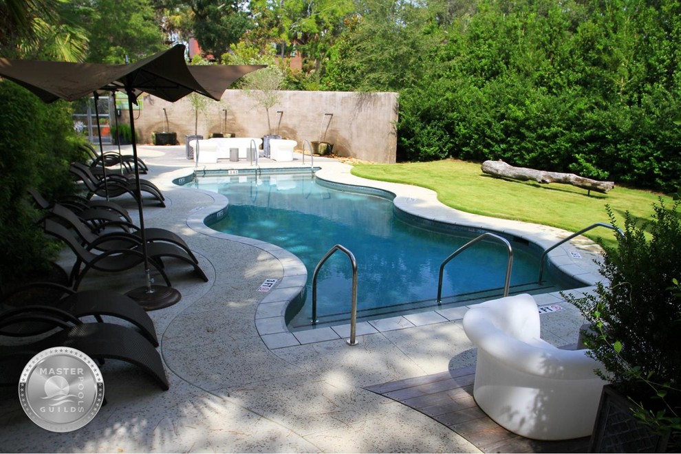 На фото: бассейн произвольной формы на внутреннем дворе в стиле фьюжн с покрытием из бетонных плит