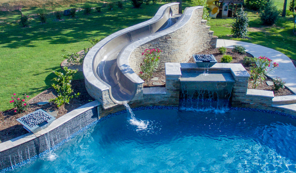 This is an example of a large back custom shaped swimming pool in Dallas with stamped concrete.