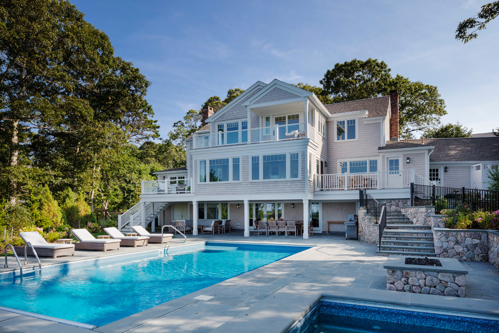 Esempio di una grande piscina naturale stile marino rettangolare dietro casa con una vasca idromassaggio e pavimentazioni in pietra naturale