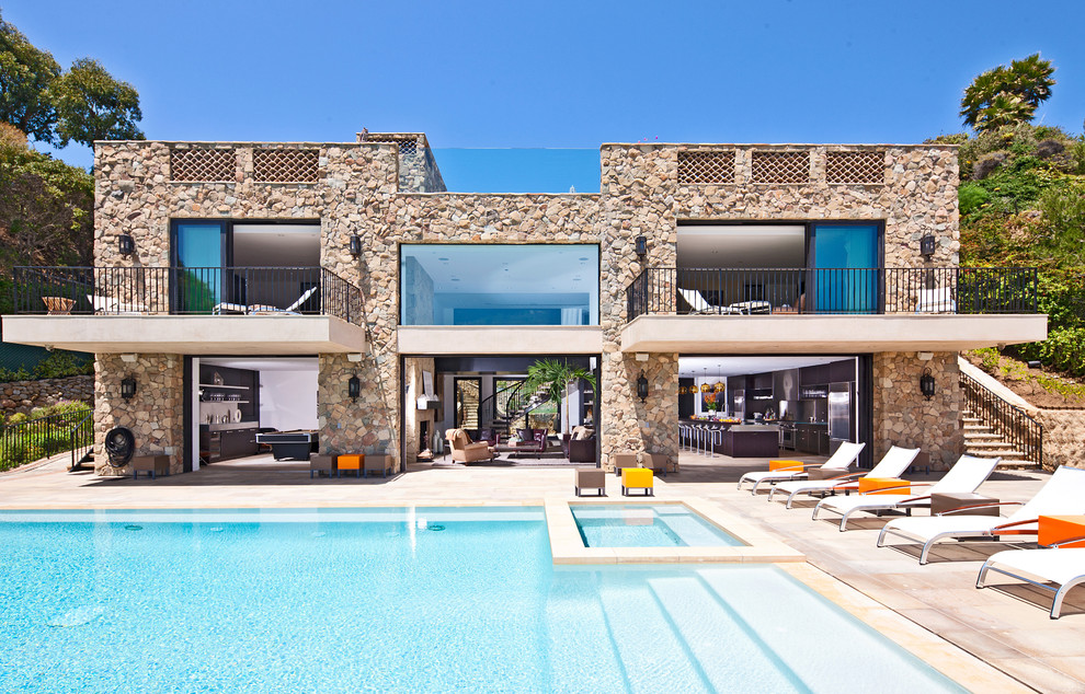 Ispirazione per una grande piscina a sfioro infinito minimal rettangolare dietro casa con pavimentazioni in pietra naturale e una vasca idromassaggio