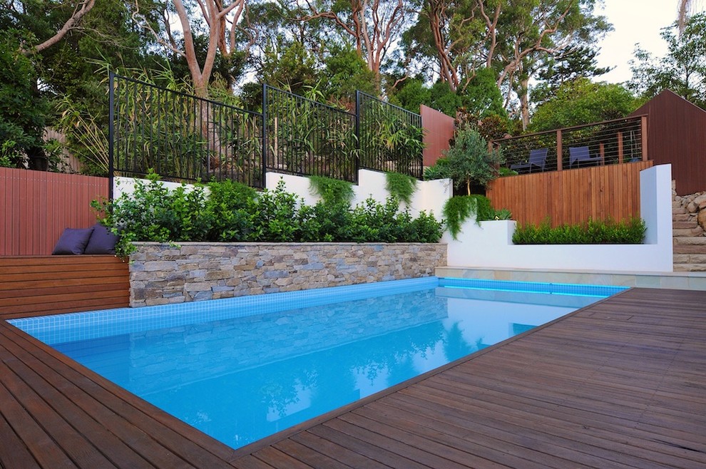 На фото: прямоугольный бассейн на заднем дворе в стиле неоклассика (современная классика) с настилом и забором