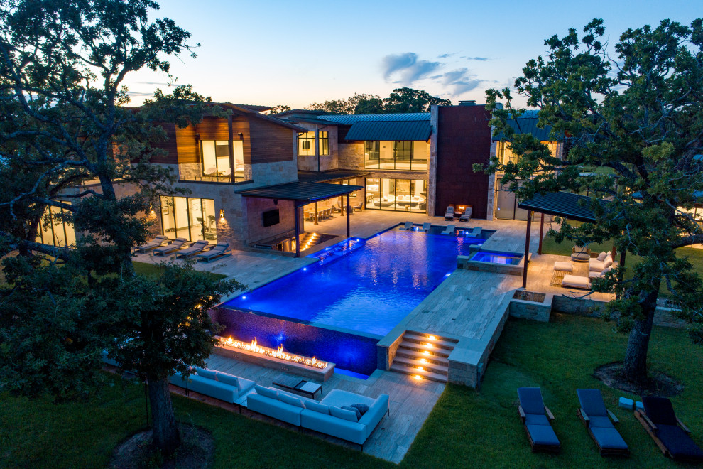 Imagen de piscina con fuente infinita clásica renovada extra grande rectangular en patio trasero con adoquines de piedra natural
