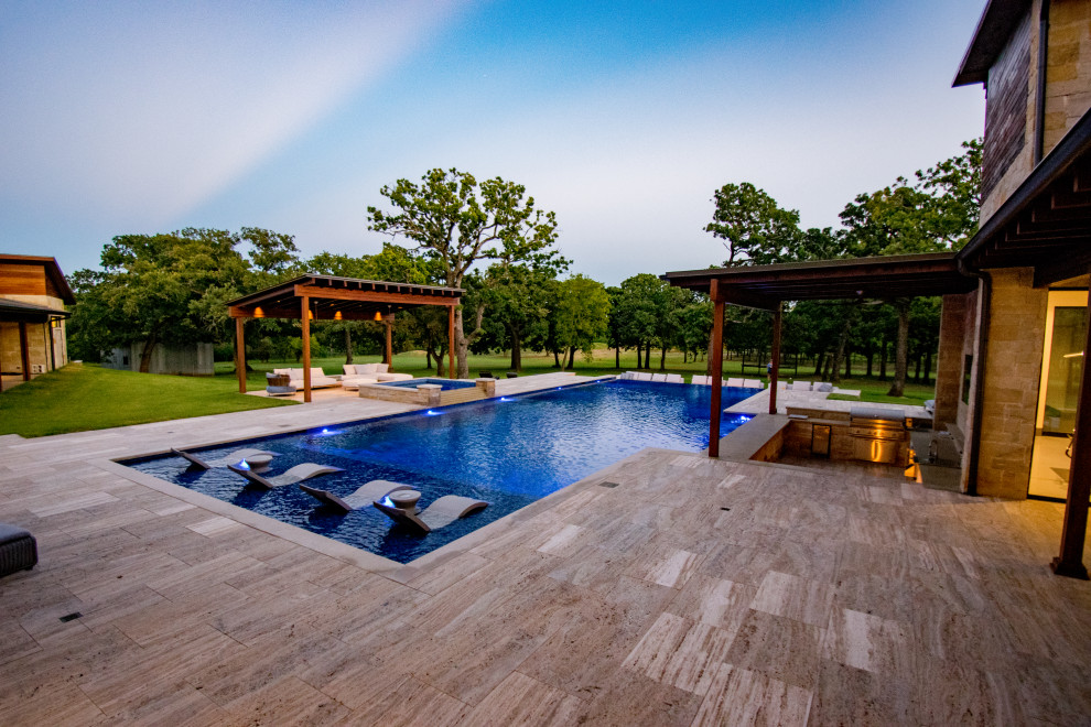 Inspiration for an expansive traditional back rectangular infinity swimming pool in Dallas with a water feature and natural stone paving.