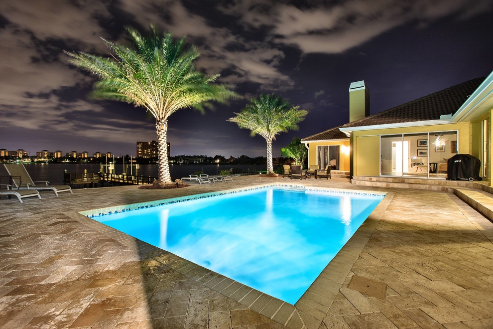 Foto de piscina alargada clásica de tamaño medio rectangular en patio trasero con suelo de baldosas