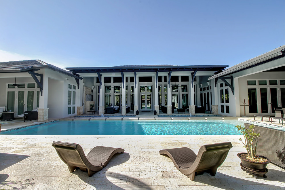 Imagen de piscina tradicional renovada grande rectangular en patio trasero con adoquines de hormigón
