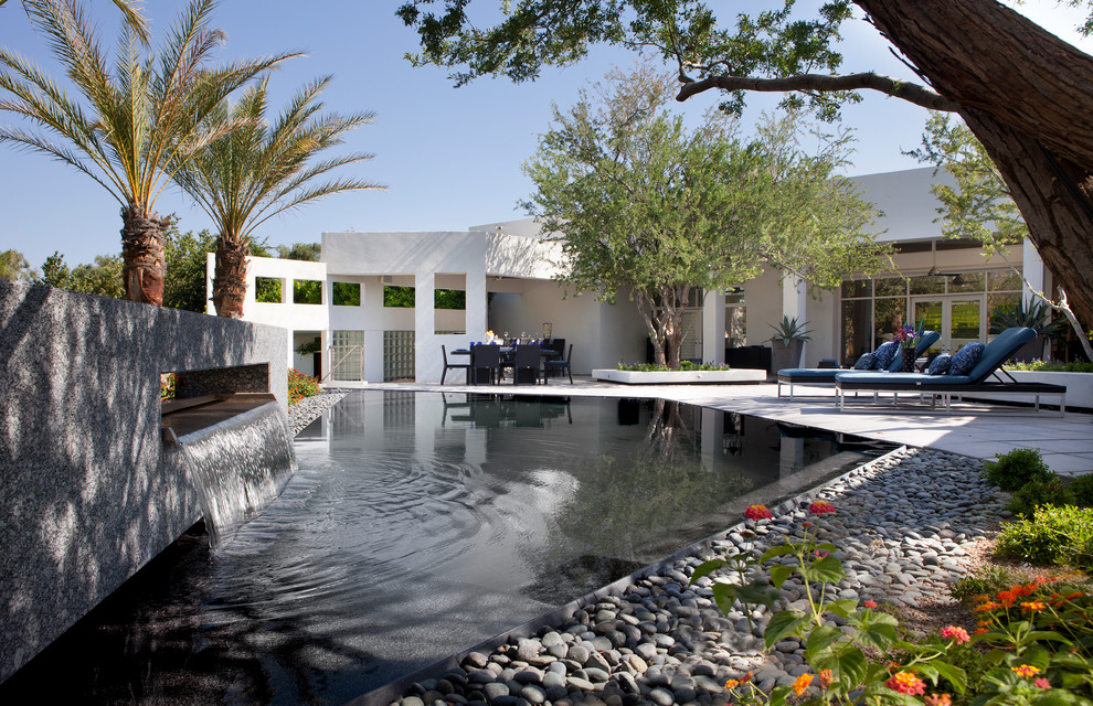 Foto di una grande piscina tradizionale personalizzata dietro casa con lastre di cemento e fontane