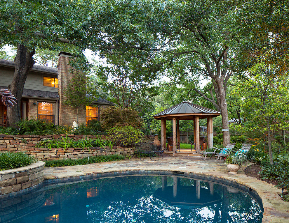 Klassischer Pool hinter dem Haus in Nierenform mit Natursteinplatten in Dallas