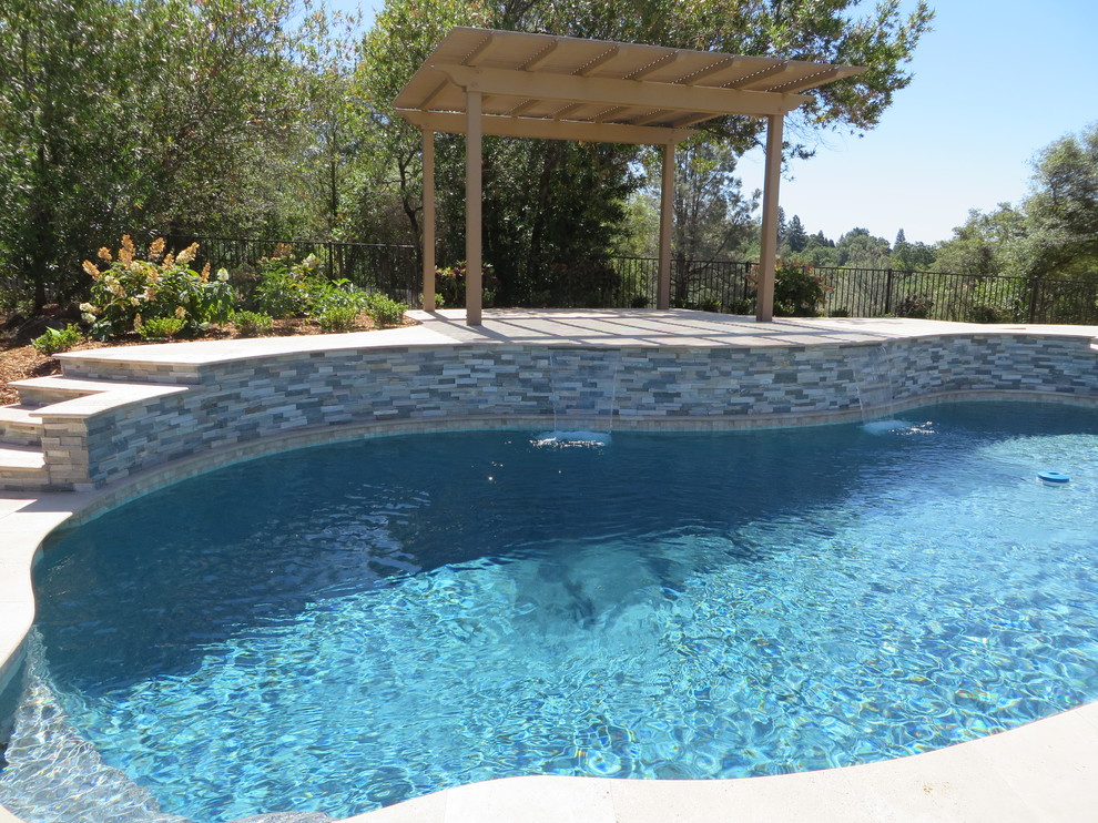 Idée de décoration pour une grande piscine arrière méditerranéenne sur mesure avec des pavés en pierre naturelle.