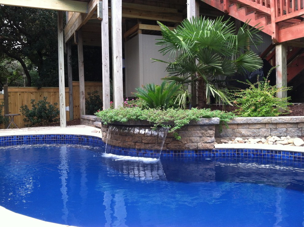 Foto de piscina con fuente actual grande a medida en patio trasero con adoquines de piedra natural