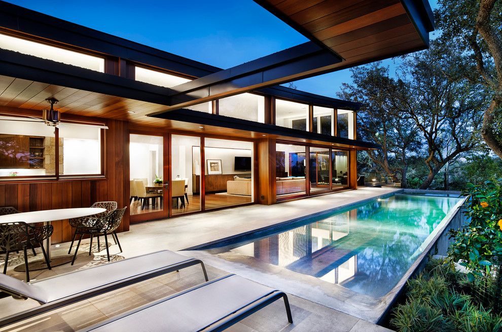 Modernes Sportbecken hinter dem Haus in rechteckiger Form mit Natursteinplatten in Austin