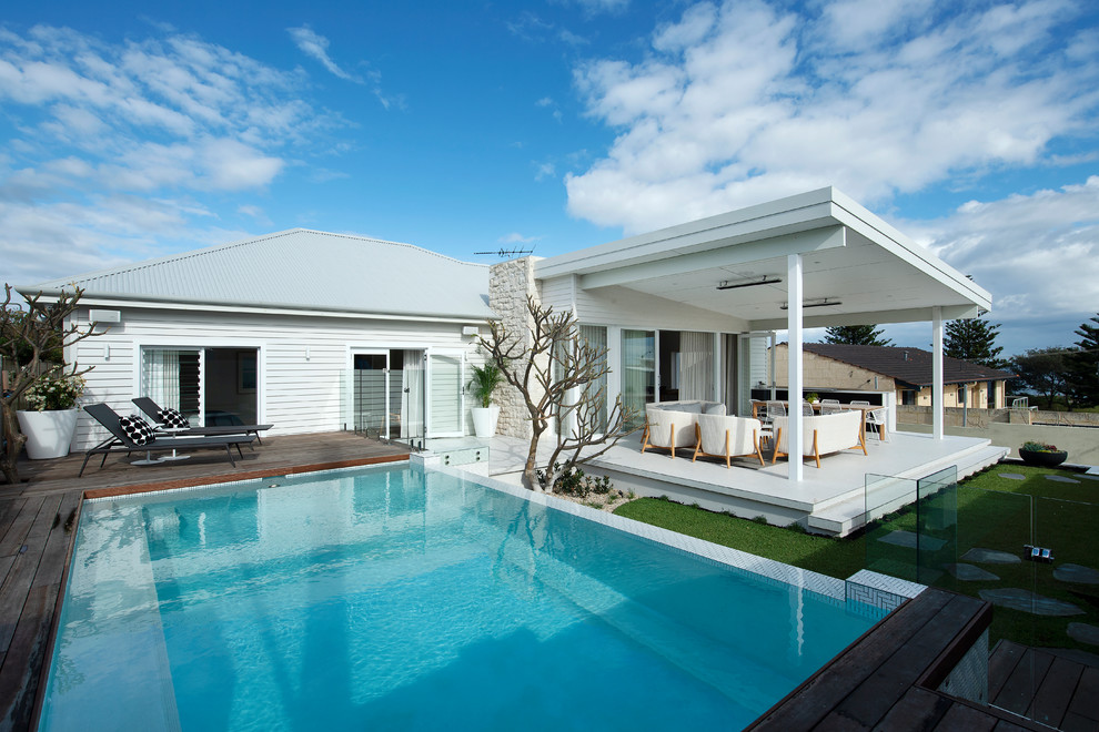 Réalisation d'une piscine à débordement et avant de taille moyenne et rectangle avec une terrasse en bois.