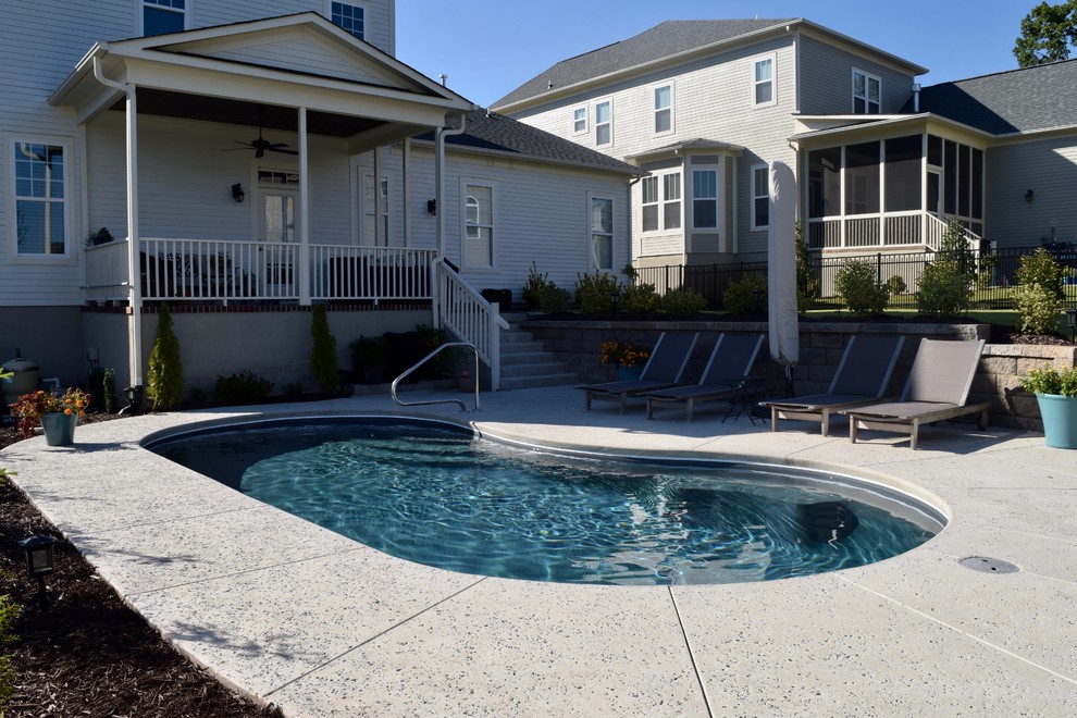 Modelo de piscina alargada minimalista de tamaño medio tipo riñón en patio trasero con losas de hormigón