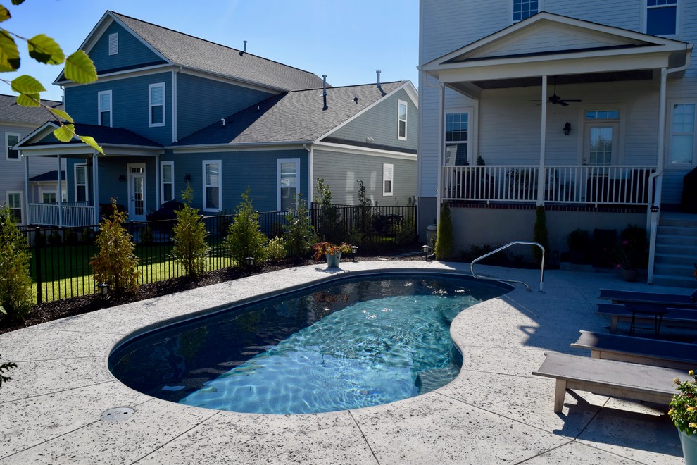 Immagine di una piscina monocorsia minimalista a "C" di medie dimensioni e dietro casa con lastre di cemento