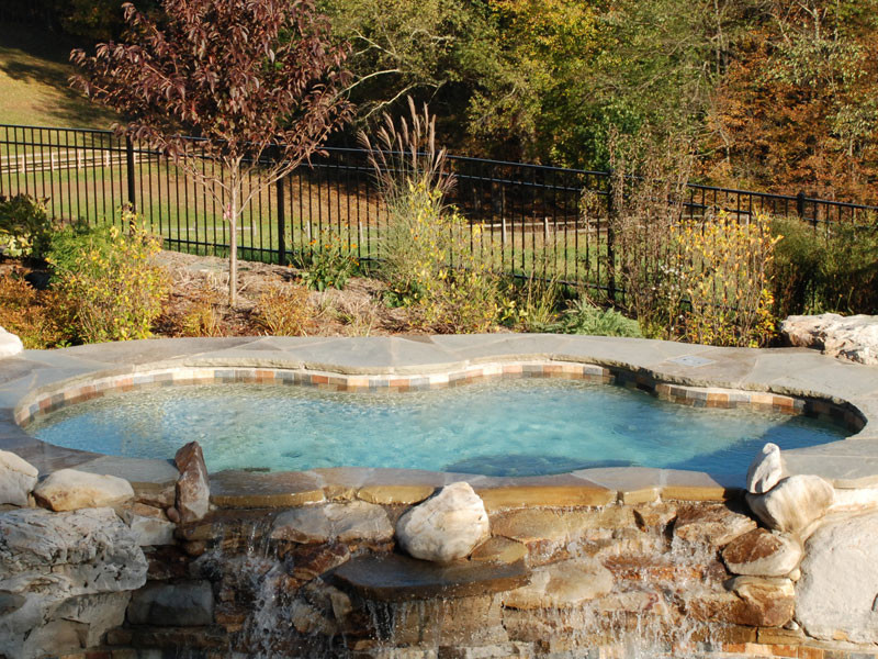 Aménagement d'une piscine arrière contemporaine en forme de haricot de taille moyenne avec un point d'eau et des pavés en pierre naturelle.