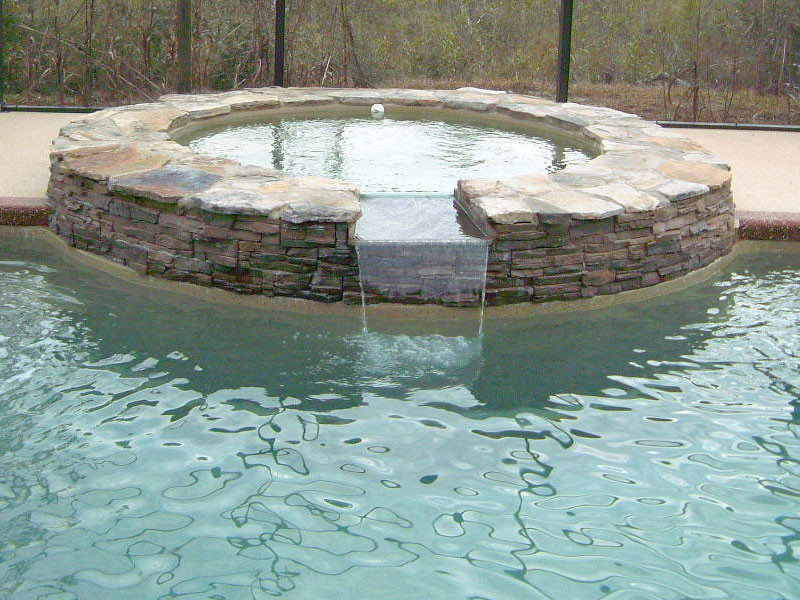Immagine di una grande piscina tradizionale rotonda dietro casa con una vasca idromassaggio e pavimentazioni in cemento