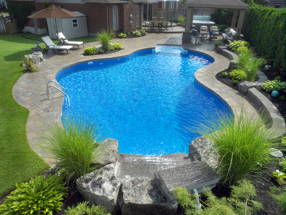 Modelo de piscina con fuente natural contemporánea grande a medida en patio trasero con adoquines de hormigón