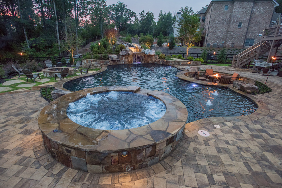 Foto di un'ampia piscina naturale tropicale personalizzata dietro casa con una vasca idromassaggio e pavimentazioni in pietra naturale