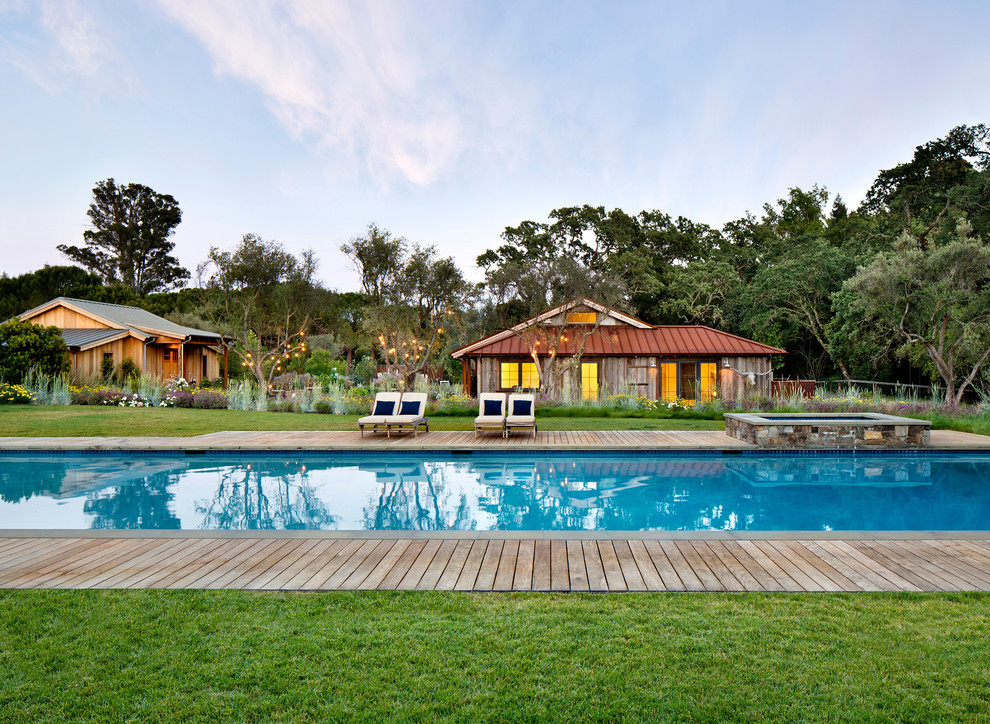 Modelo de casa de la piscina y piscina alargada campestre rectangular en patio trasero con entablado