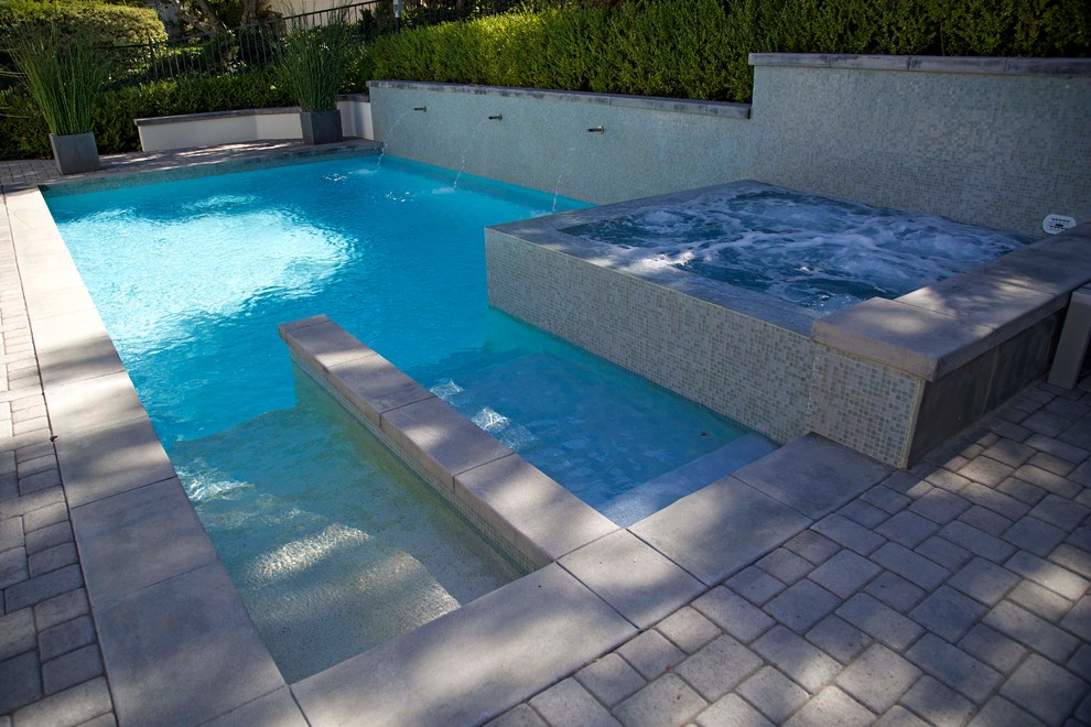 Foto de piscina minimalista de tamaño medio rectangular en patio lateral con adoquines de hormigón