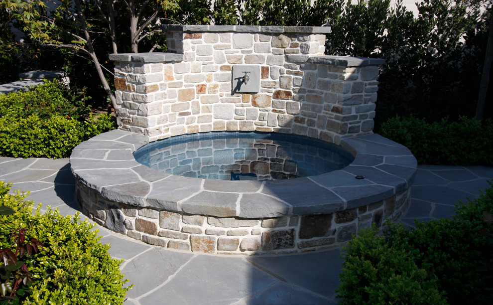 Ejemplo de piscinas y jacuzzis tradicionales pequeños redondeados en patio trasero con adoquines de piedra natural