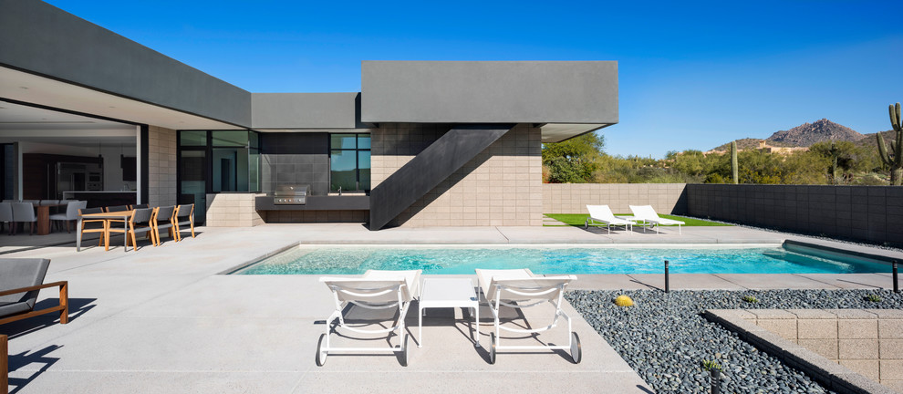 Bild på en mellanstor funkis rektangulär pool på baksidan av huset, med betongplatta