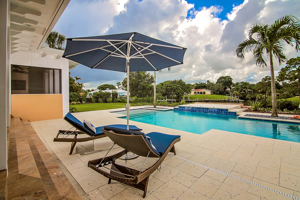 Großer Pool hinter dem Haus in rechteckiger Form mit Wasserspiel und Betonplatten in Miami