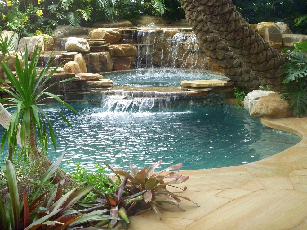 Example of an island style backyard stone and custom-shaped natural pool fountain design in Miami