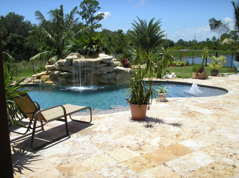 Large world-inspired back custom shaped natural swimming pool in Miami with a water feature.