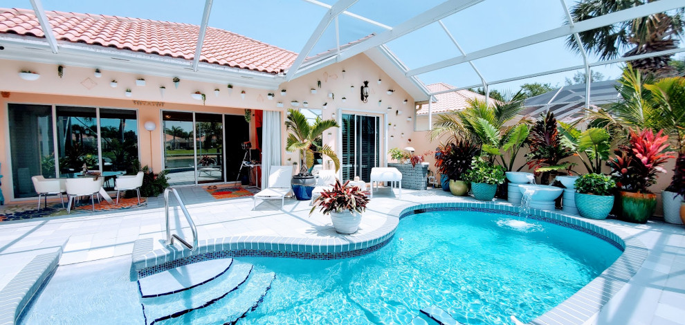 Ejemplo de piscina bohemia de tamaño medio tipo riñón en patio trasero con paisajismo de piscina y losas de hormigón