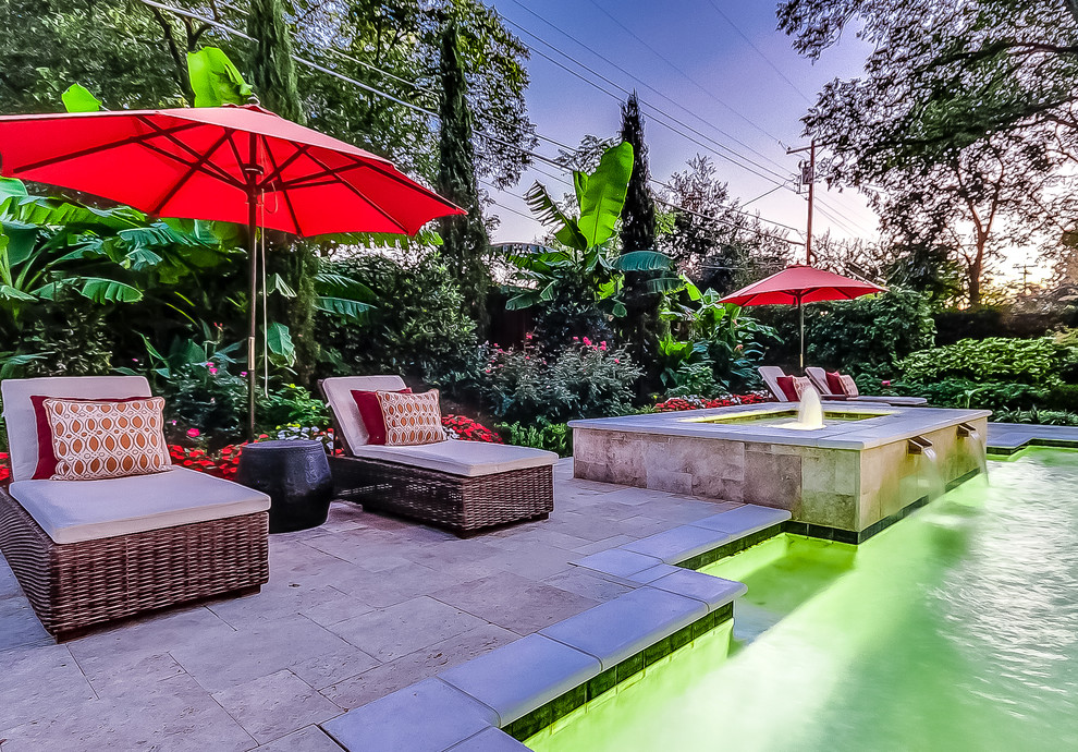Ejemplo de piscinas y jacuzzis tropicales a medida en patio trasero con adoquines de piedra natural