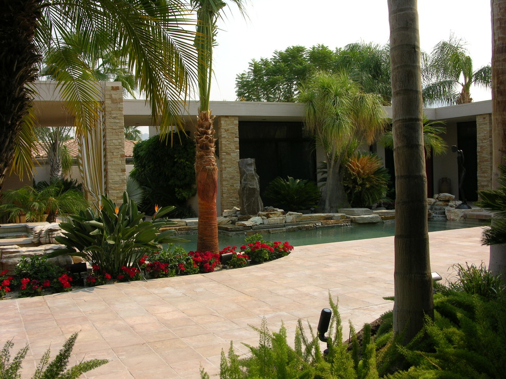 Diseño de piscina natural mediterránea grande en forma de L en patio con adoquines de piedra natural