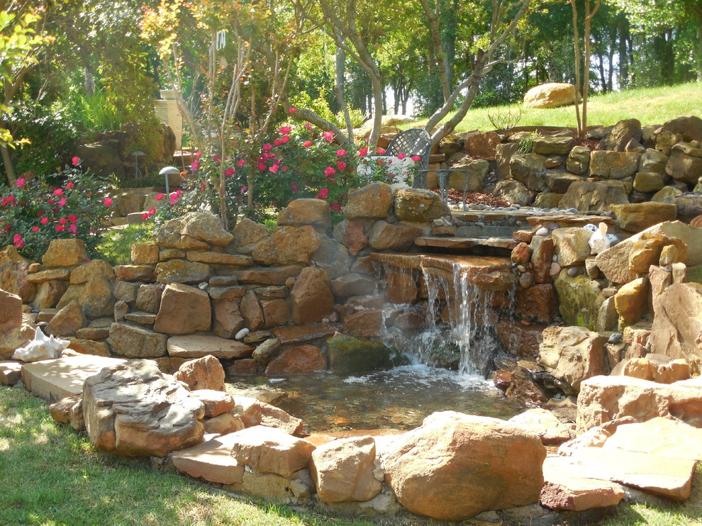 Ispirazione per un ampio giardino tropicale dietro casa con fontane