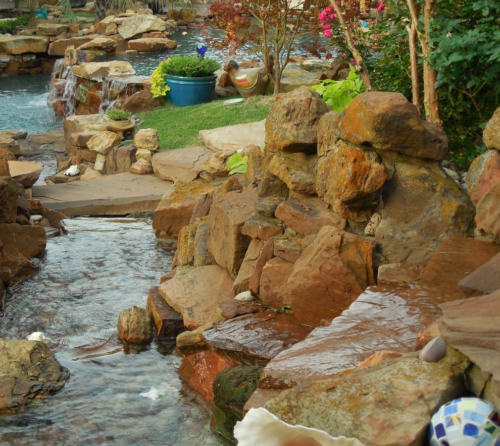 Idee per un'ampia piscina naturale tropicale personalizzata dietro casa con fontane e cemento stampato