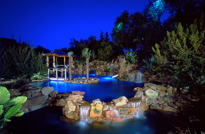 Foto di un'ampia piscina naturale tropicale personalizzata dietro casa con fontane e cemento stampato