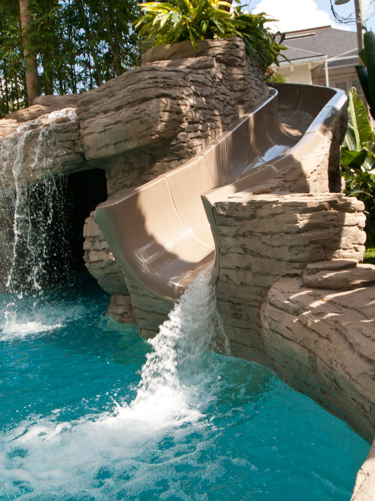 Aménagement d'une très grande piscine exotique sur mesure avec des pavés en béton et un bain bouillonnant.