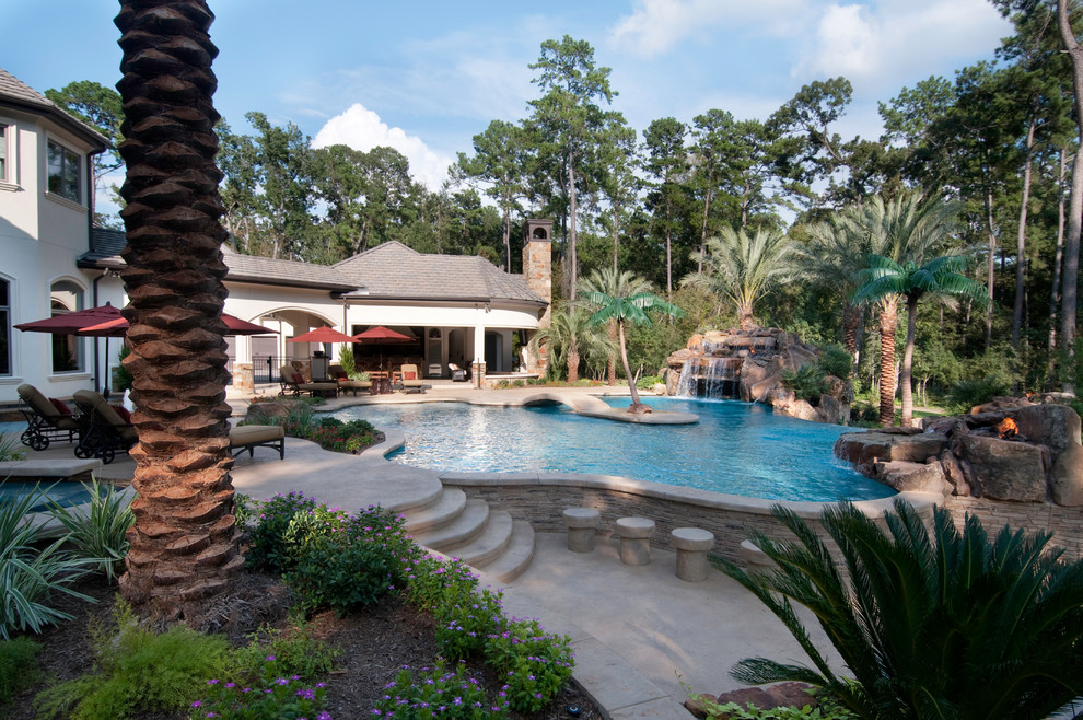 Ispirazione per un'ampia piscina monocorsia tropicale personalizzata dietro casa con cemento stampato e fontane