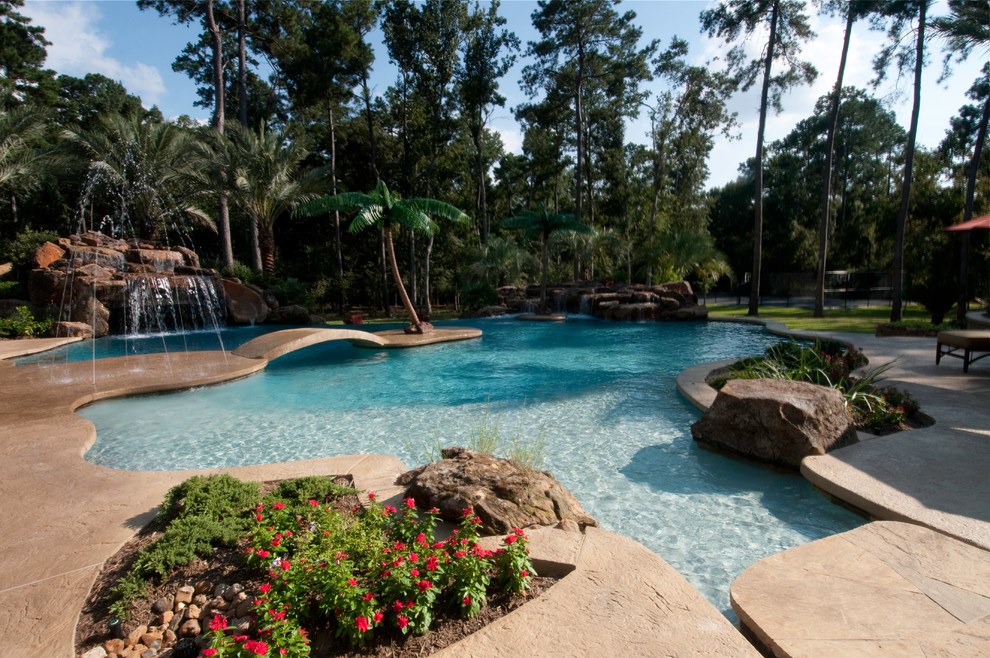 Imagen de piscina con fuente alargada tropical extra grande a medida en patio trasero con suelo de hormigón estampado