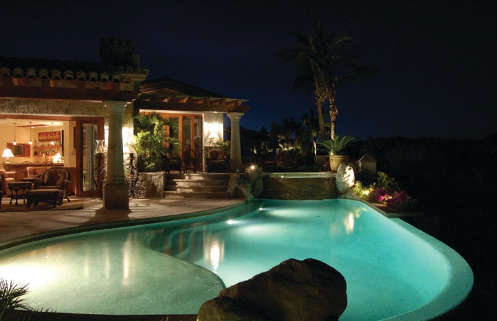 This is an example of an expansive world-inspired back kidney-shaped hot tub in Denver with natural stone paving.