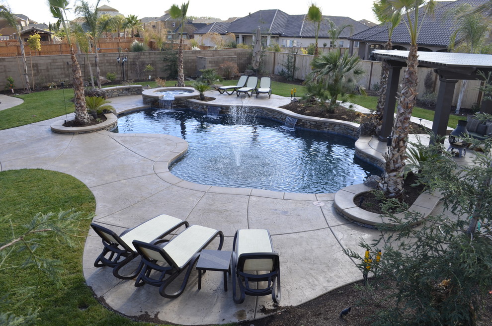 Пример оригинального дизайна: большой естественный бассейн произвольной формы на заднем дворе в морском стиле с покрытием из декоративного бетона и джакузи