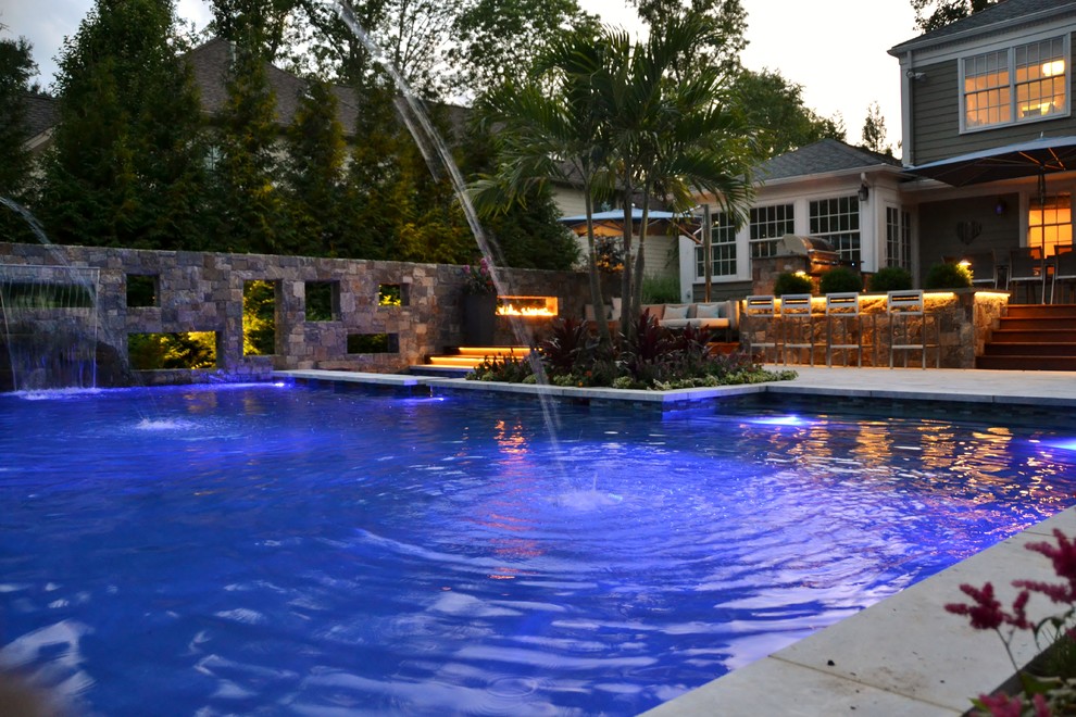 Diseño de piscina exótica de tamaño medio en forma de L en patio trasero con suelo de baldosas