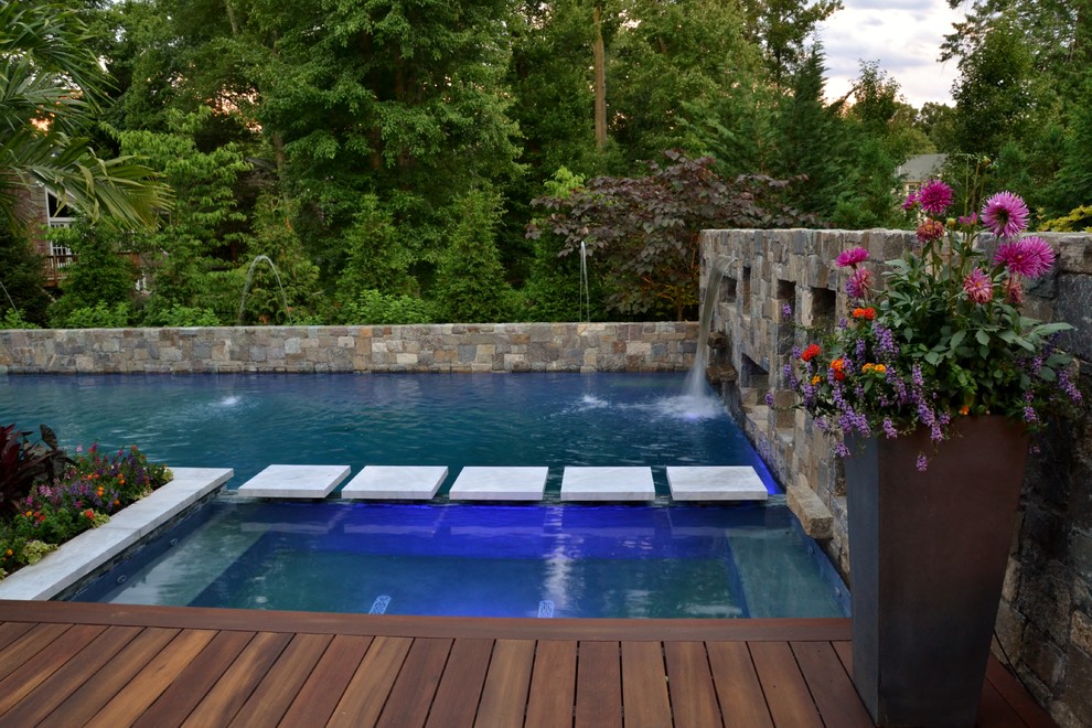Diseño de piscina exótica de tamaño medio en forma de L en patio trasero con suelo de baldosas