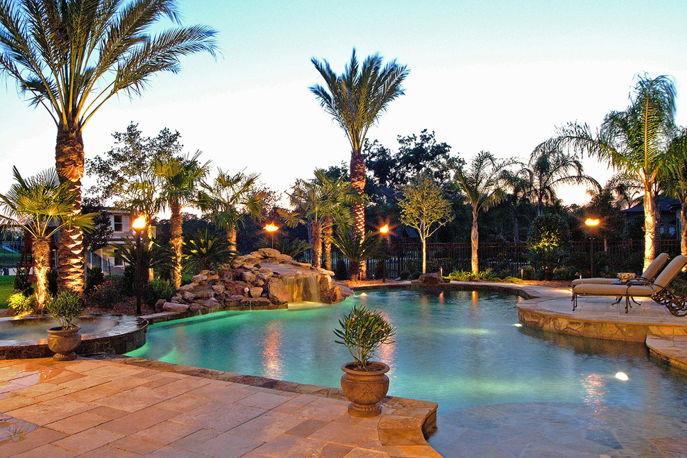 Ejemplo de piscinas y jacuzzis naturales tropicales grandes a medida en patio trasero con adoquines de piedra natural