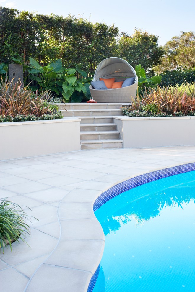 This is an example of a large contemporary back custom shaped natural swimming pool in Sydney with natural stone paving.