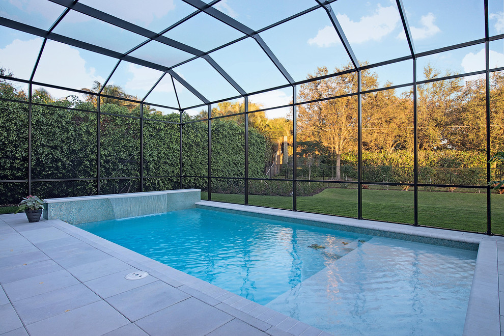 Diseño de piscina con fuente exótica grande rectangular en patio trasero con adoquines de hormigón