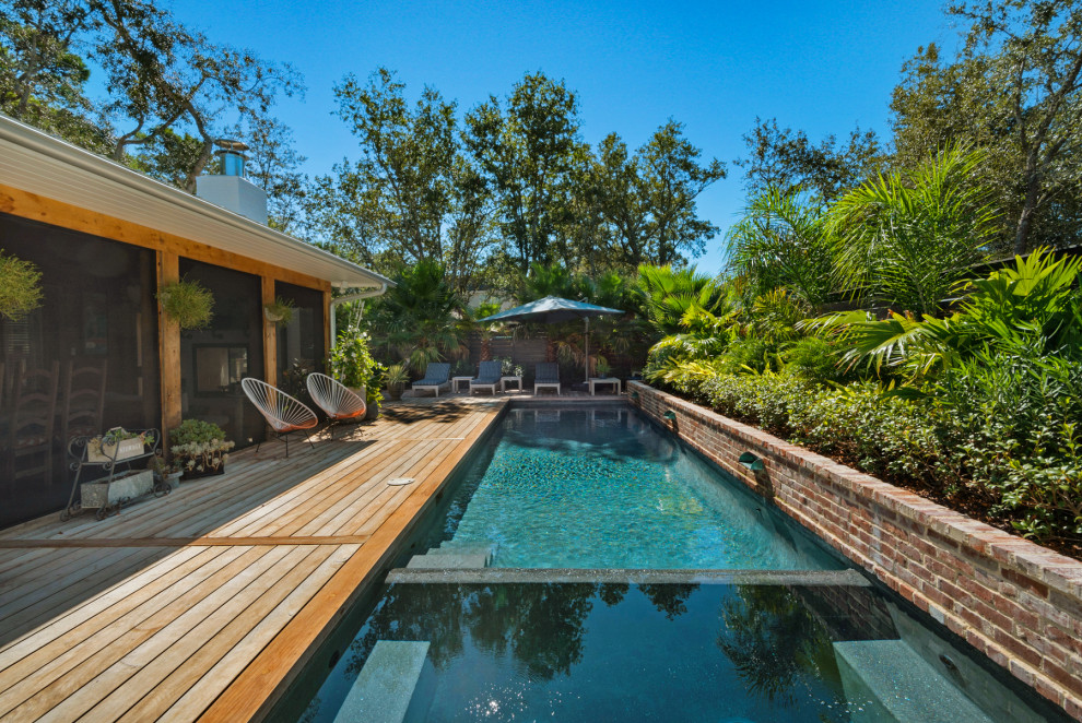 Cette image montre une petite piscine latérale ethnique rectangle avec une terrasse en bois.